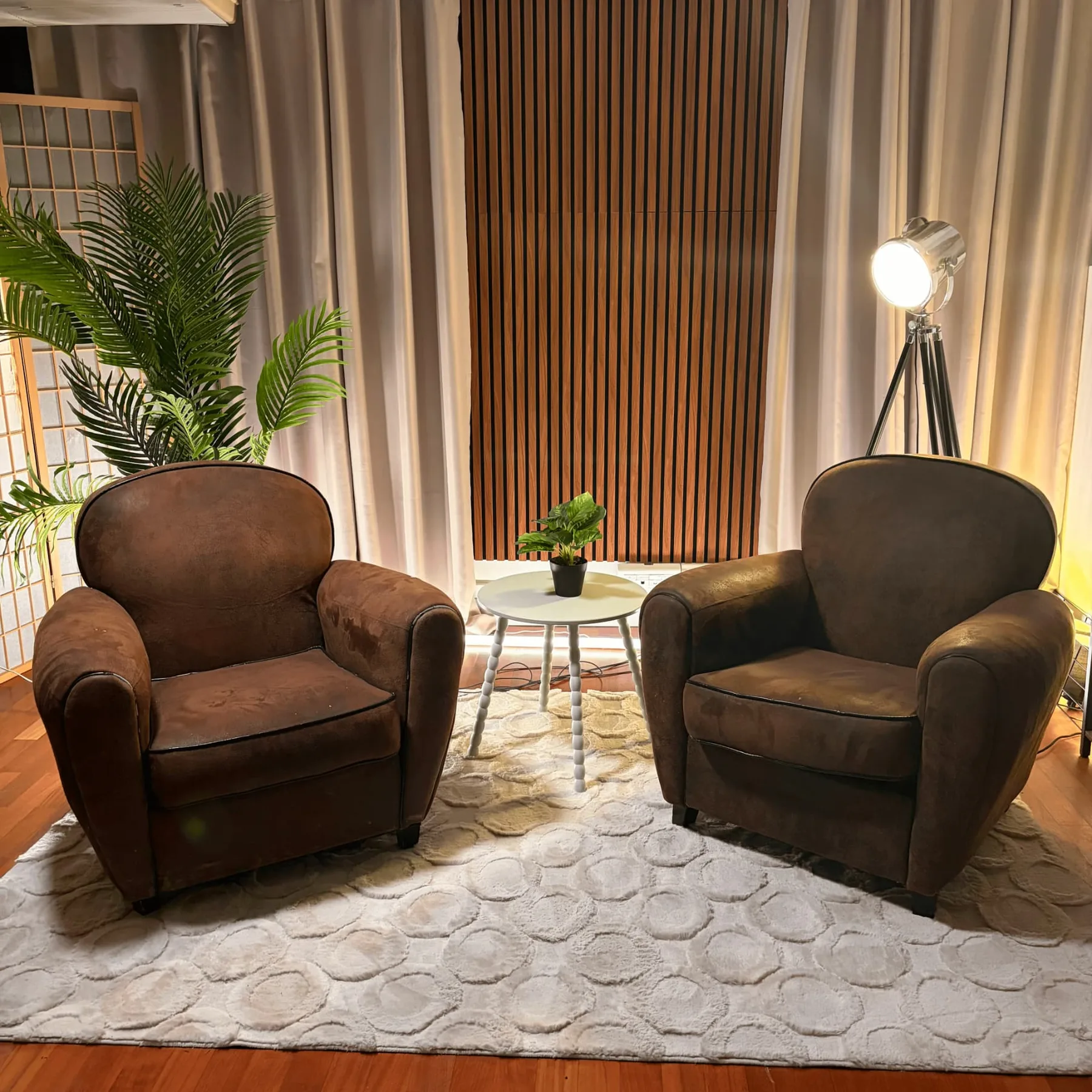 Studio Cosy : deux fauteuils club, table blanche et panneau bois